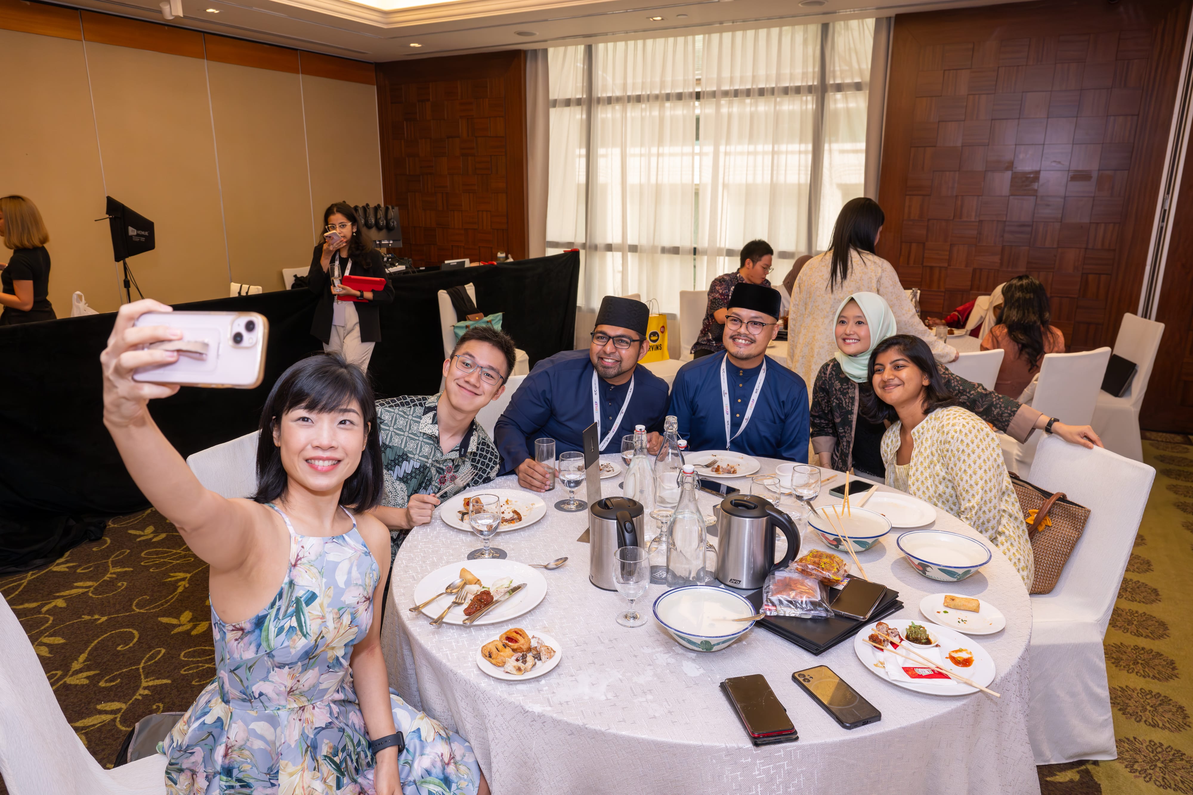 Group of people taking a group selfie in a dinner setting.